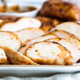 Smoked chicken breast slices on a white platter.