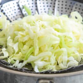 Shredded cabbage in a steamer basket.