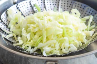 Shredded cabbage in a steamer basket.