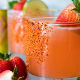 Two strawberry palomas surrounded by ice and strawberries.