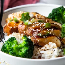 A plate of Teriyaki chicken with rice and steamed broccoli.