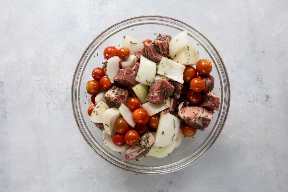 A bowl of ribeye and veggies marinating for beef kabobs.
