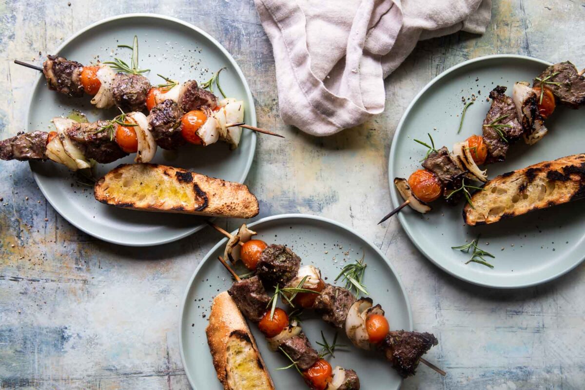 Plates full of beef kabobs and grilled bread.