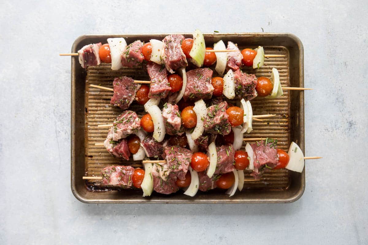 Raw beef kabob skewers on a tray.