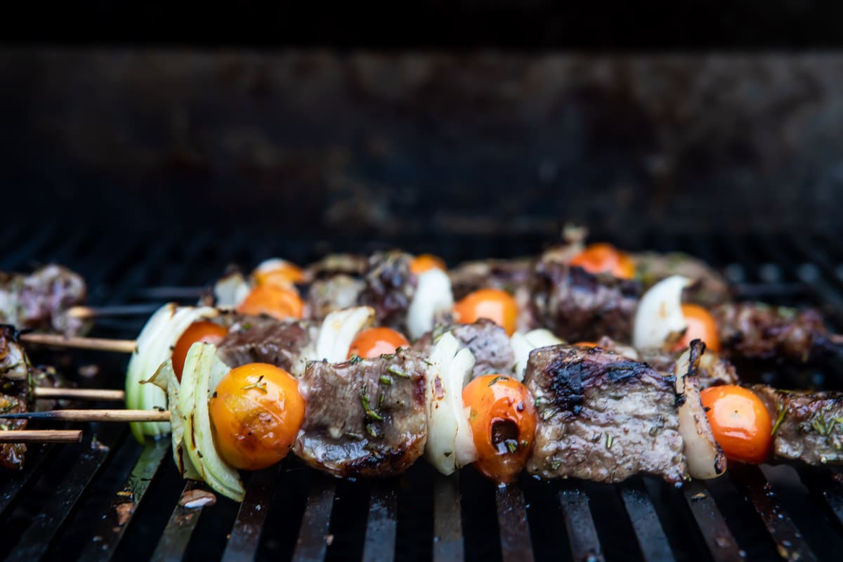Beef kabobs cooking on a grill.