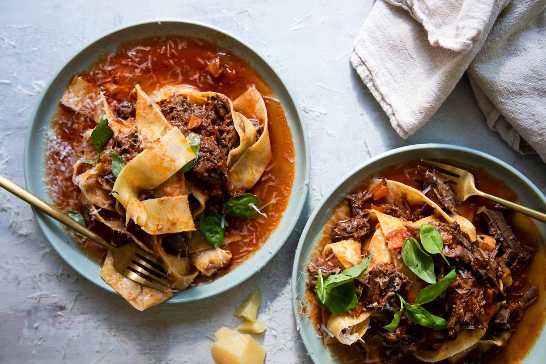 Beef ragu on two small blue plates.