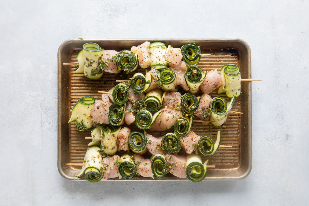 Uncooked chicken kabobs on a baking sheet.