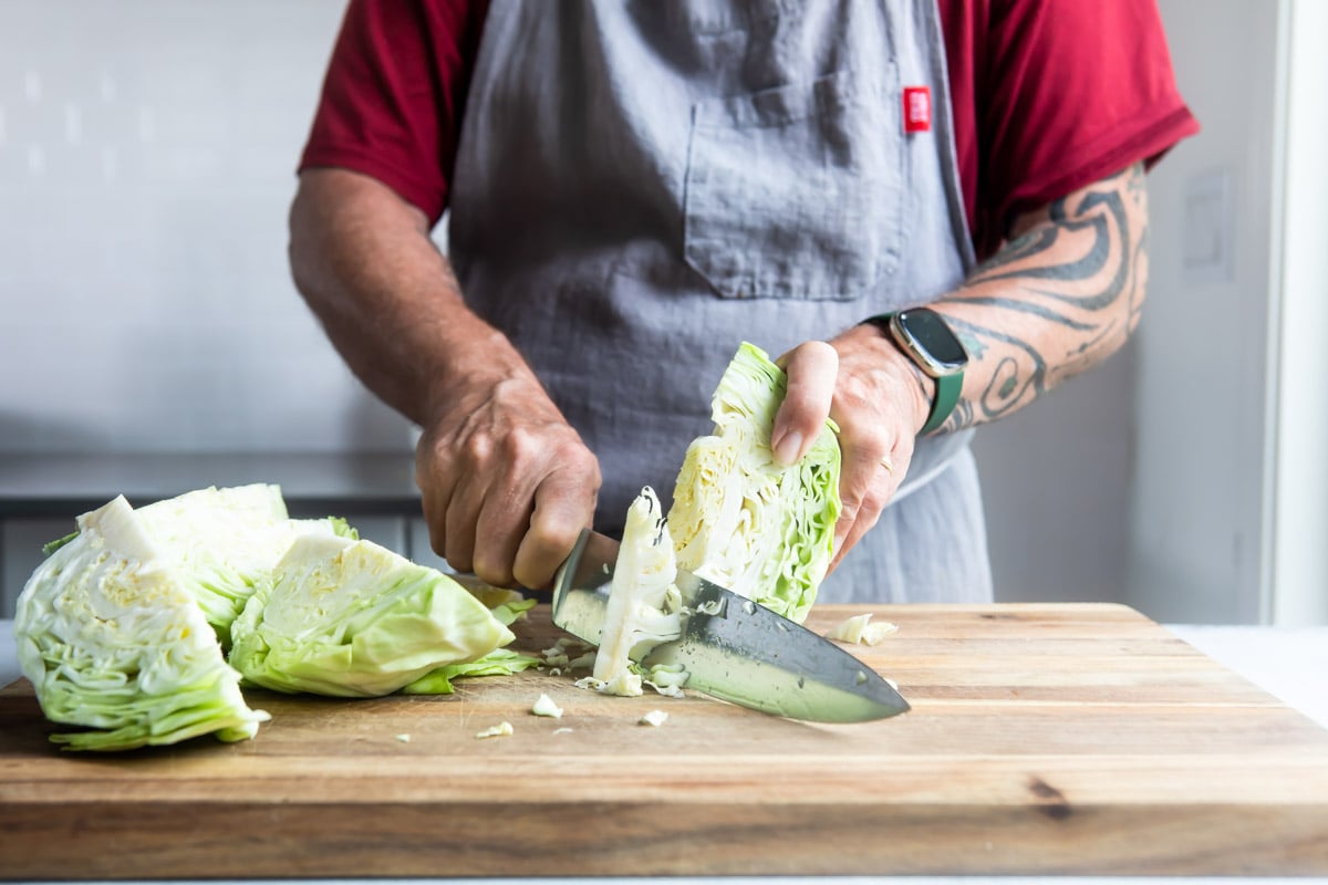Someone cutting the core out of a cabbage.