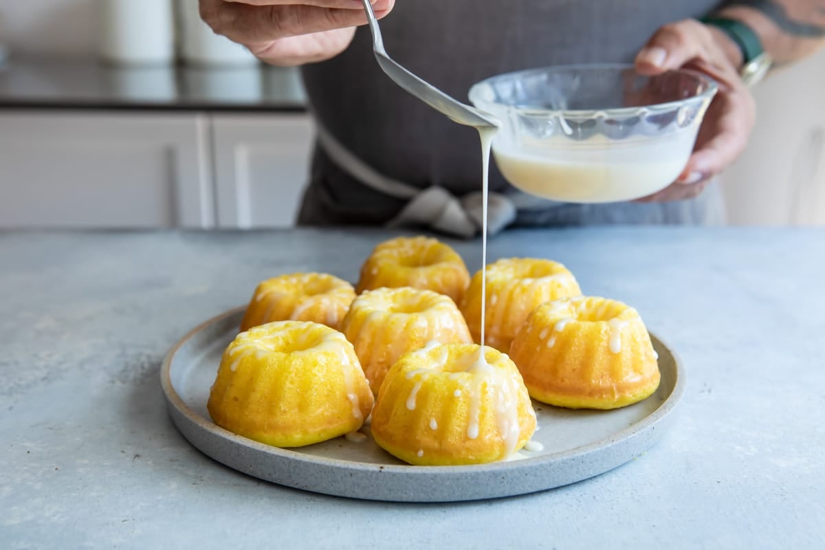 Mini Bundt cakes being drizzled with icing.