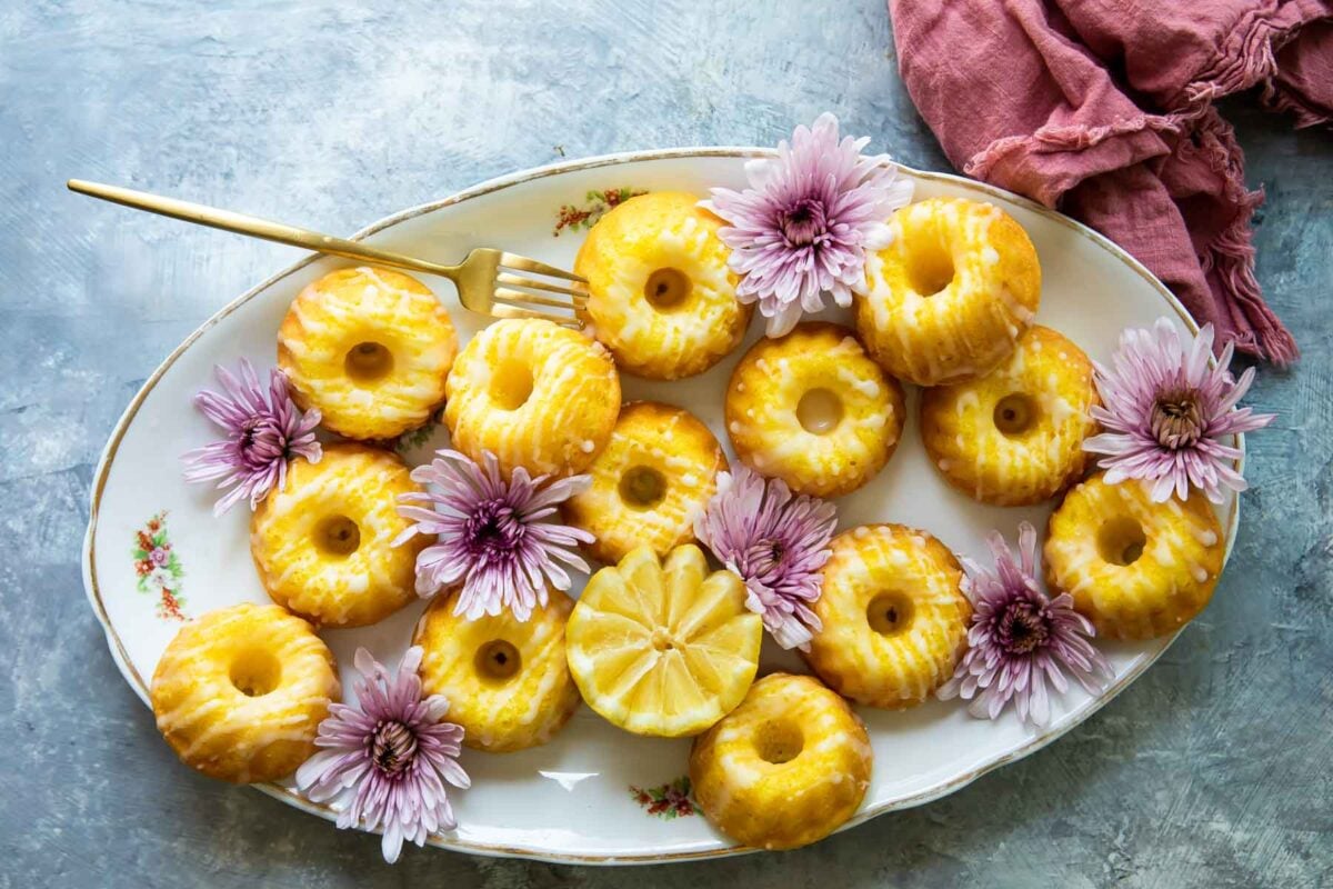 Mini bundt cakes displayed with purple flowers on a white serving platter.