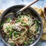 Pasta with peas and prosciutto in a silver skillet.