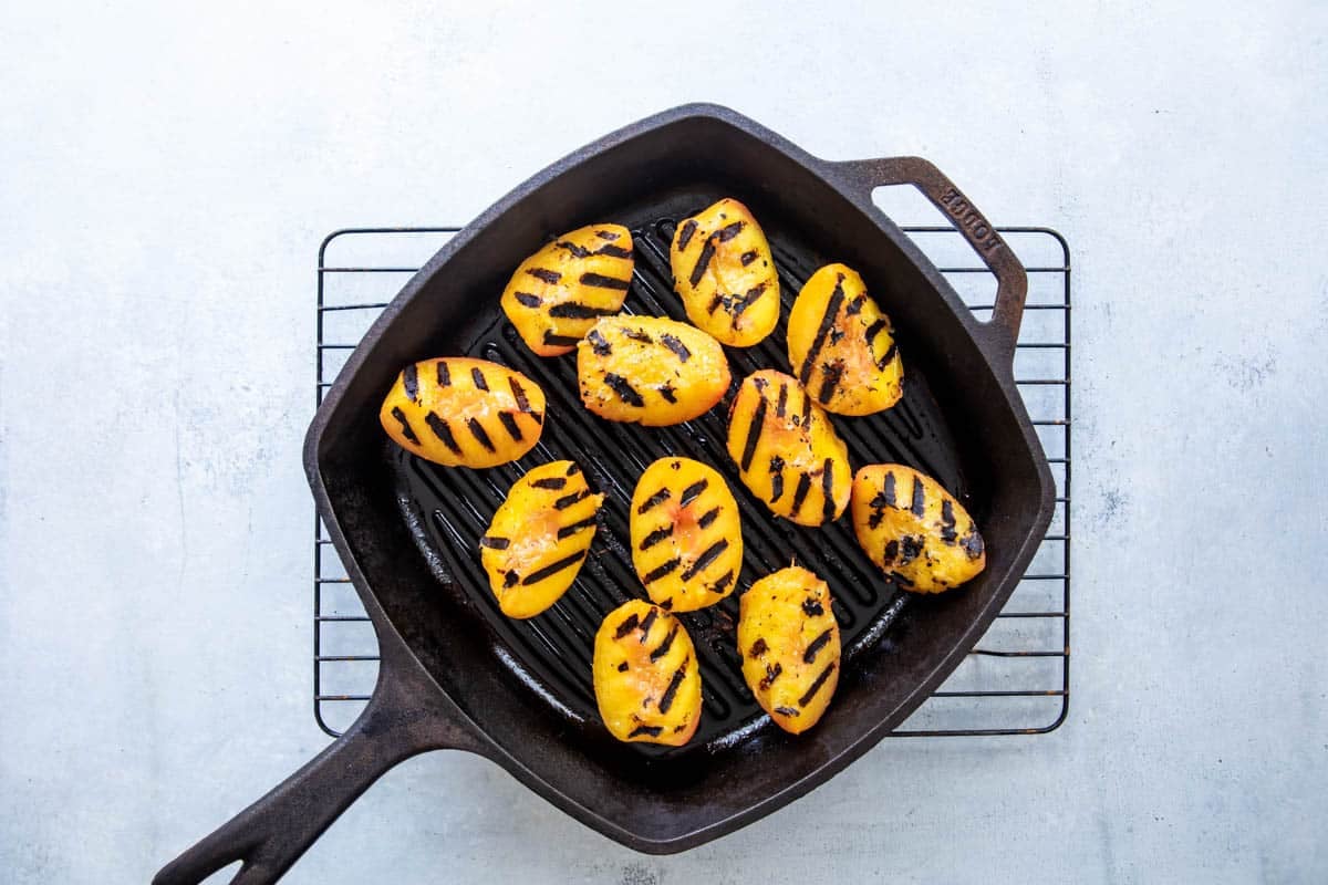 A grill pan full of grilled peaches.
