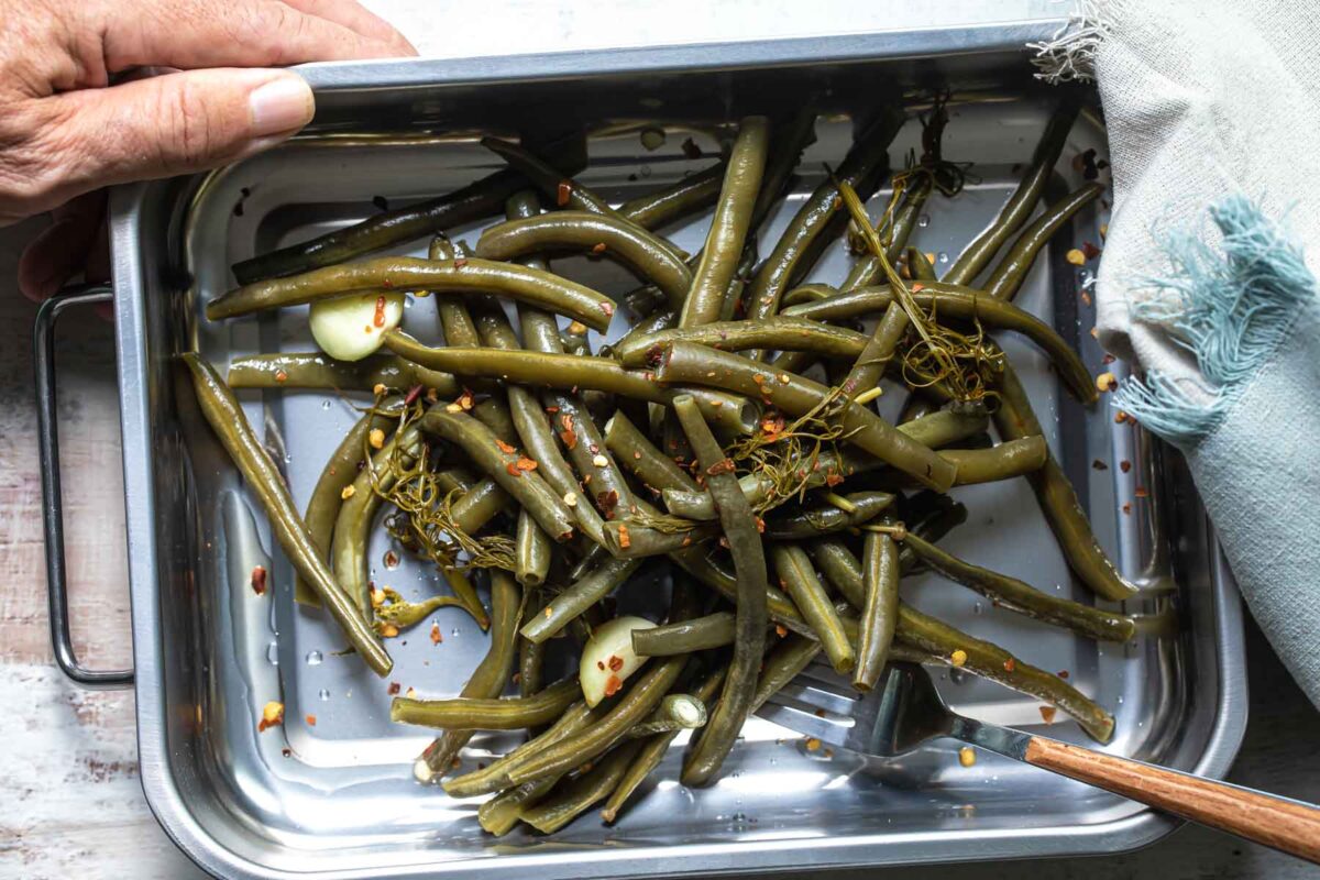 Pickled green beans in a metal pan.