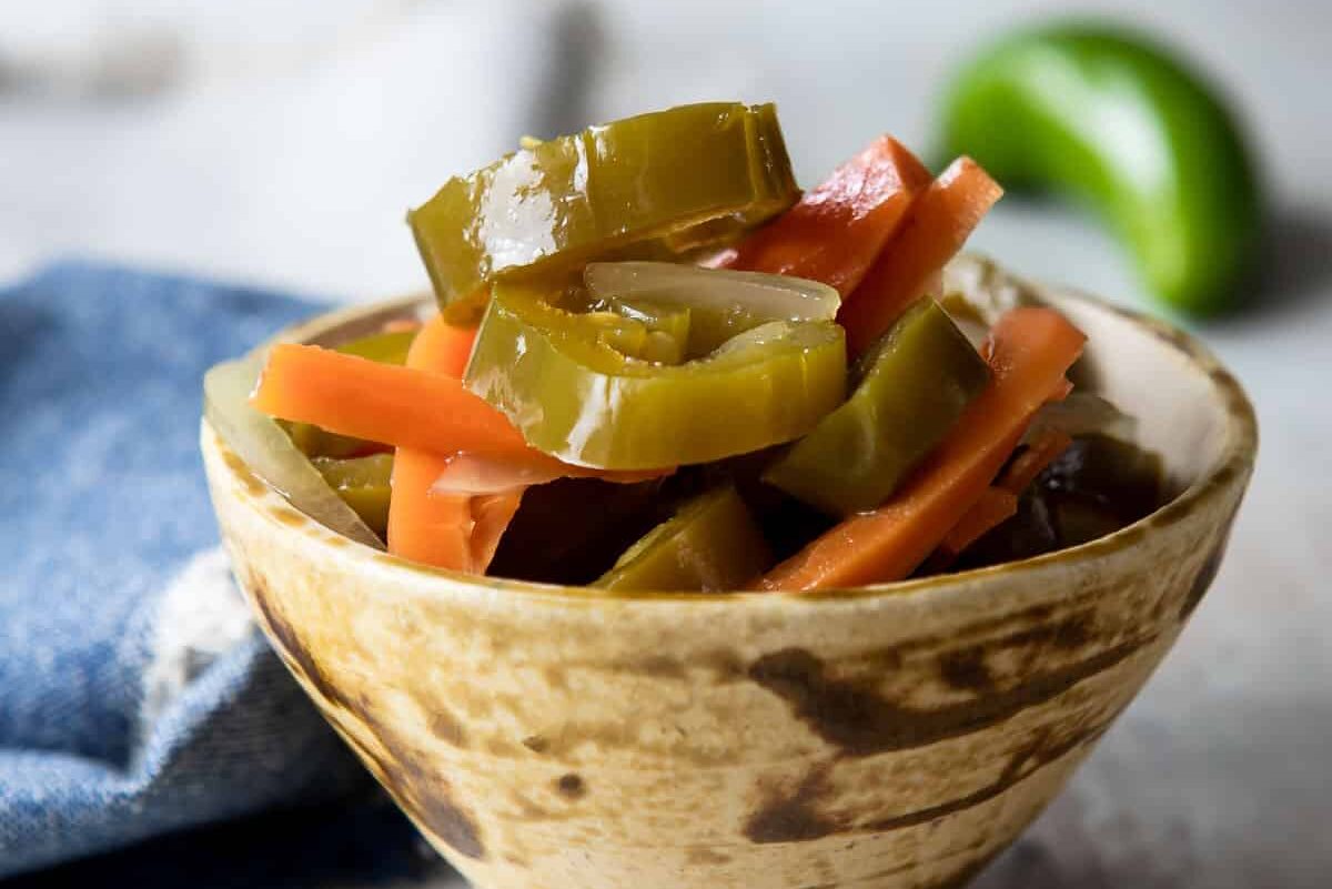 A small brown bowl with pickled jalapeños.