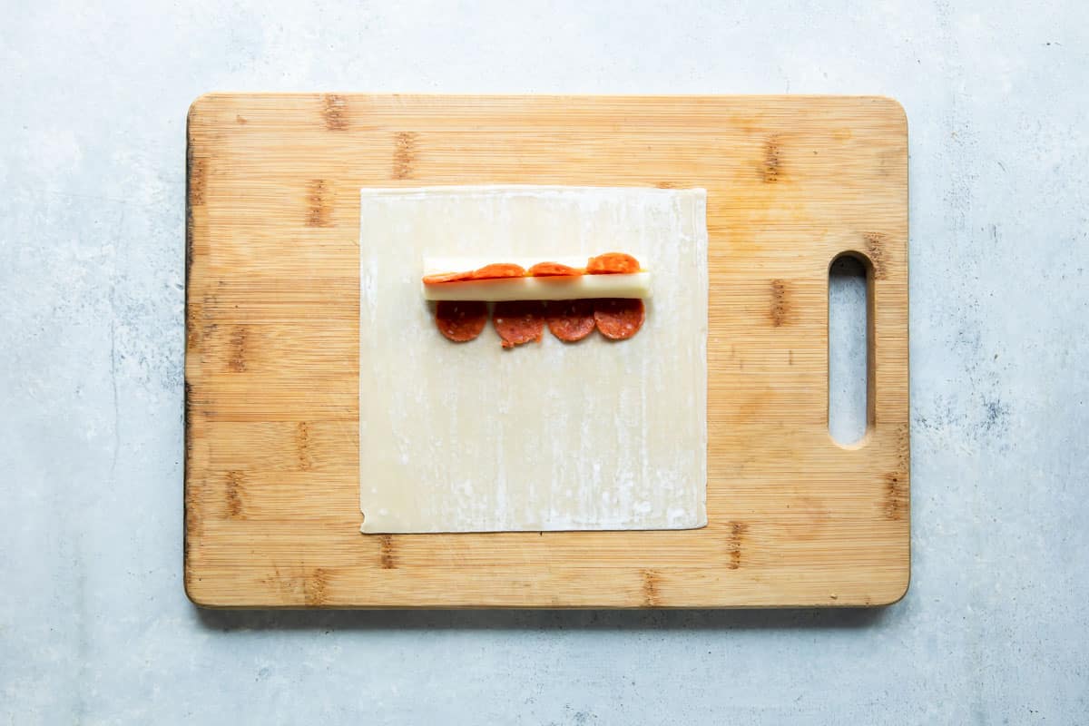 A pizza stick being assembled on a wooden cutting board.