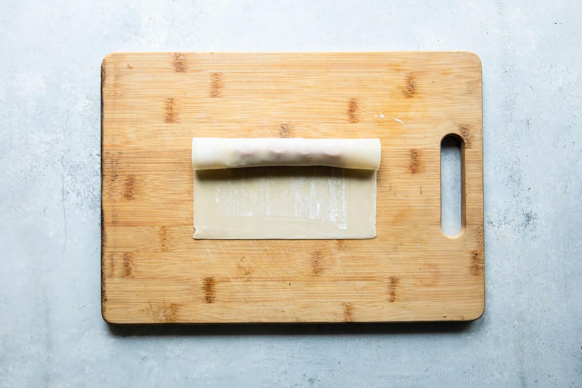 A pizza stick being assembled on a wooden cutting board.