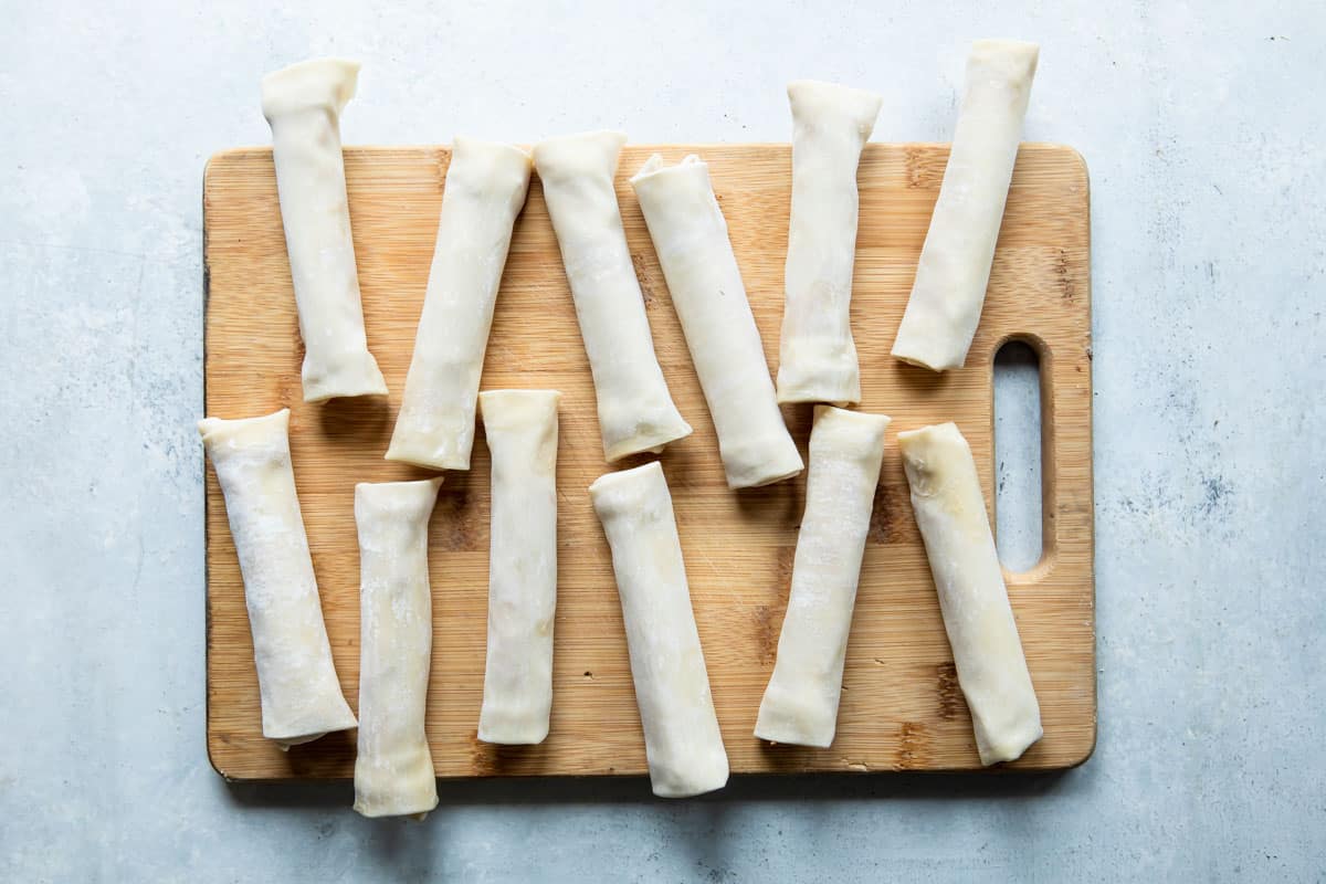 Prepared pizza sticks on a wooden cutting board before being baked.