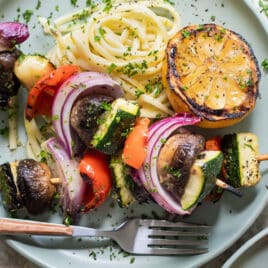A plate with veggie kabobs and pasta.