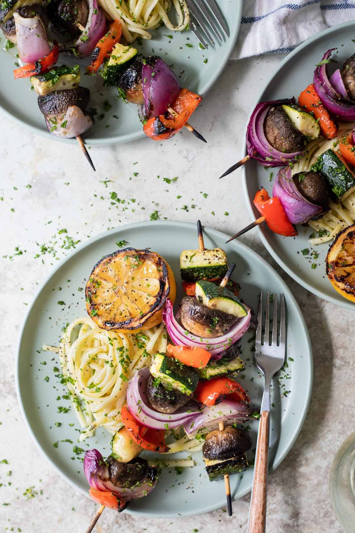 Veggie kabobs on a small plate over pasta.
