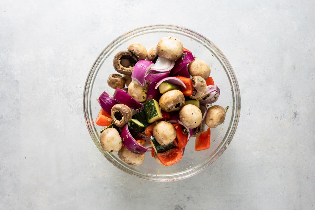 A clear bowl filled with vegetables for veggie kabobs.