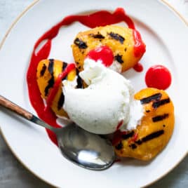 A plate of peach melba topped with raspberry coulis.