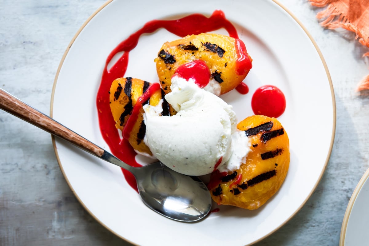 A plate of peach melba topped with raspberry coulis.