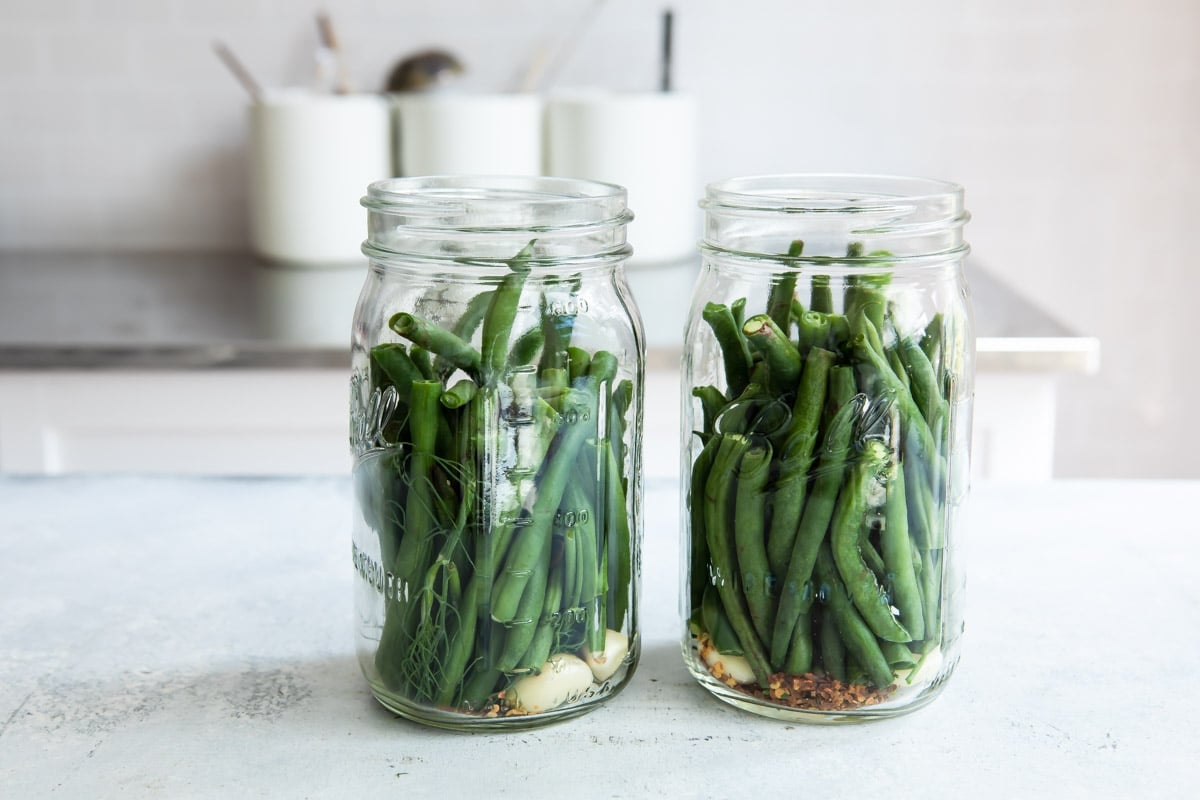 Fresh green beans in jars with garlic and spices for picking.