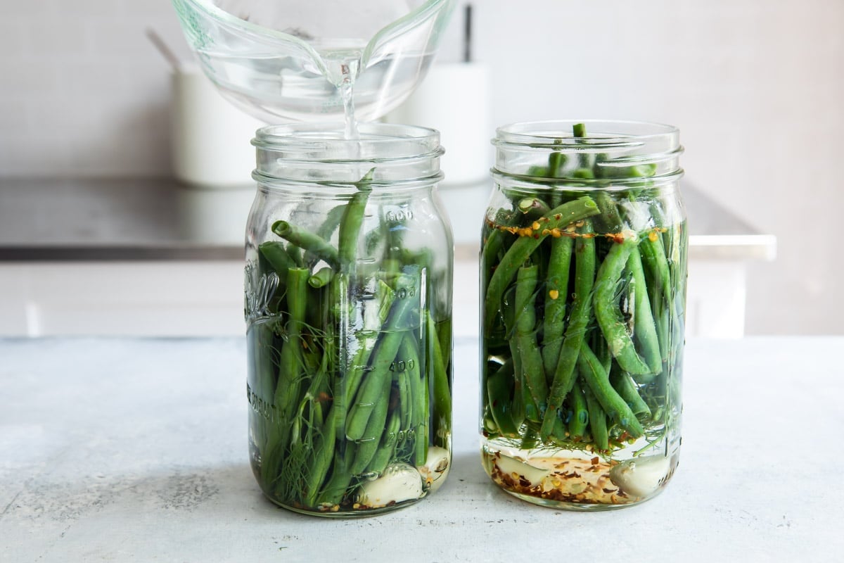 Fresh green beans in jars with garlic and spices for picking.