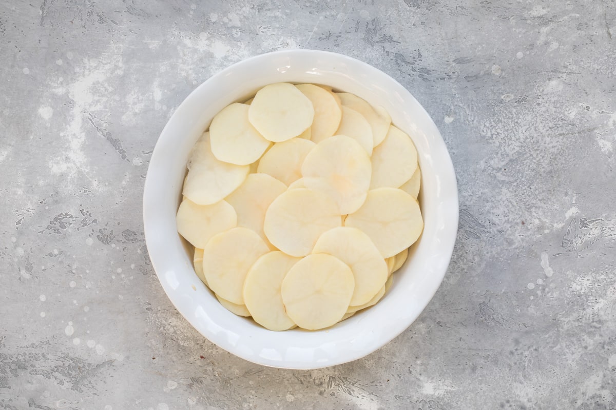 Potatoes and cheese sauce layered in a casserole dish.