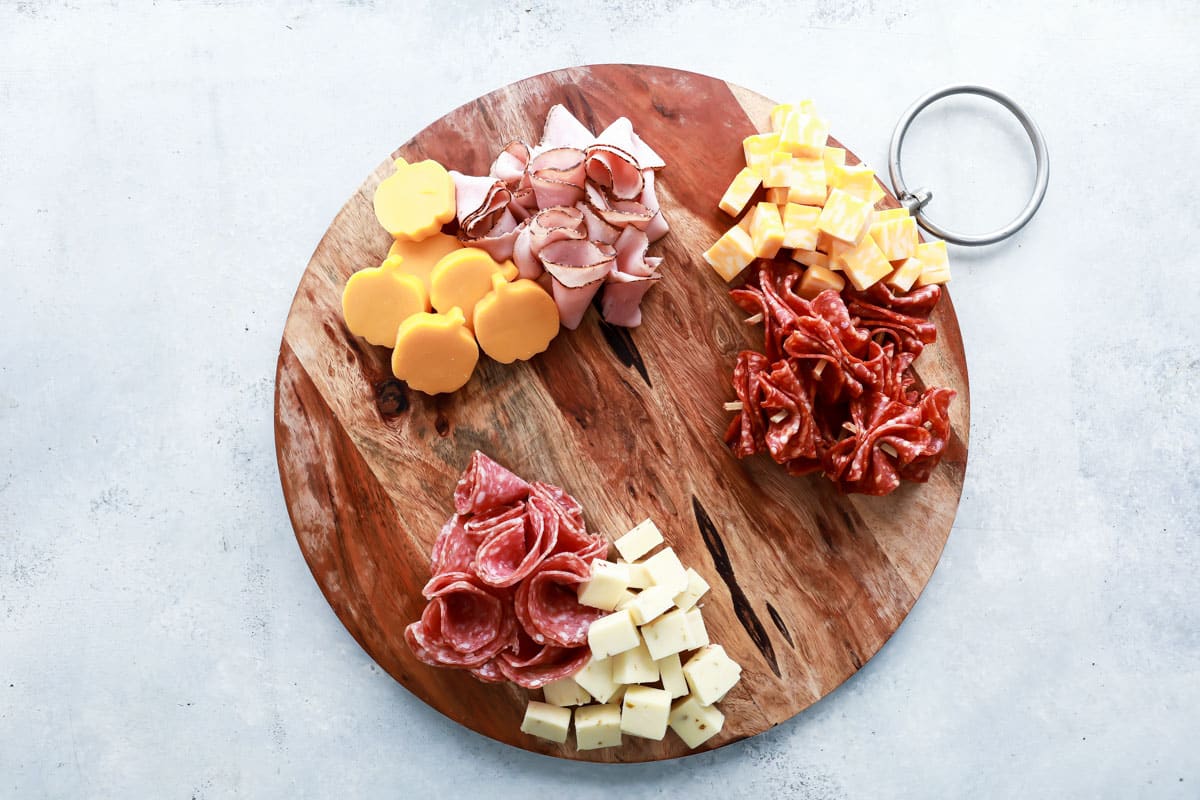 A board with meat and cheese on it.
