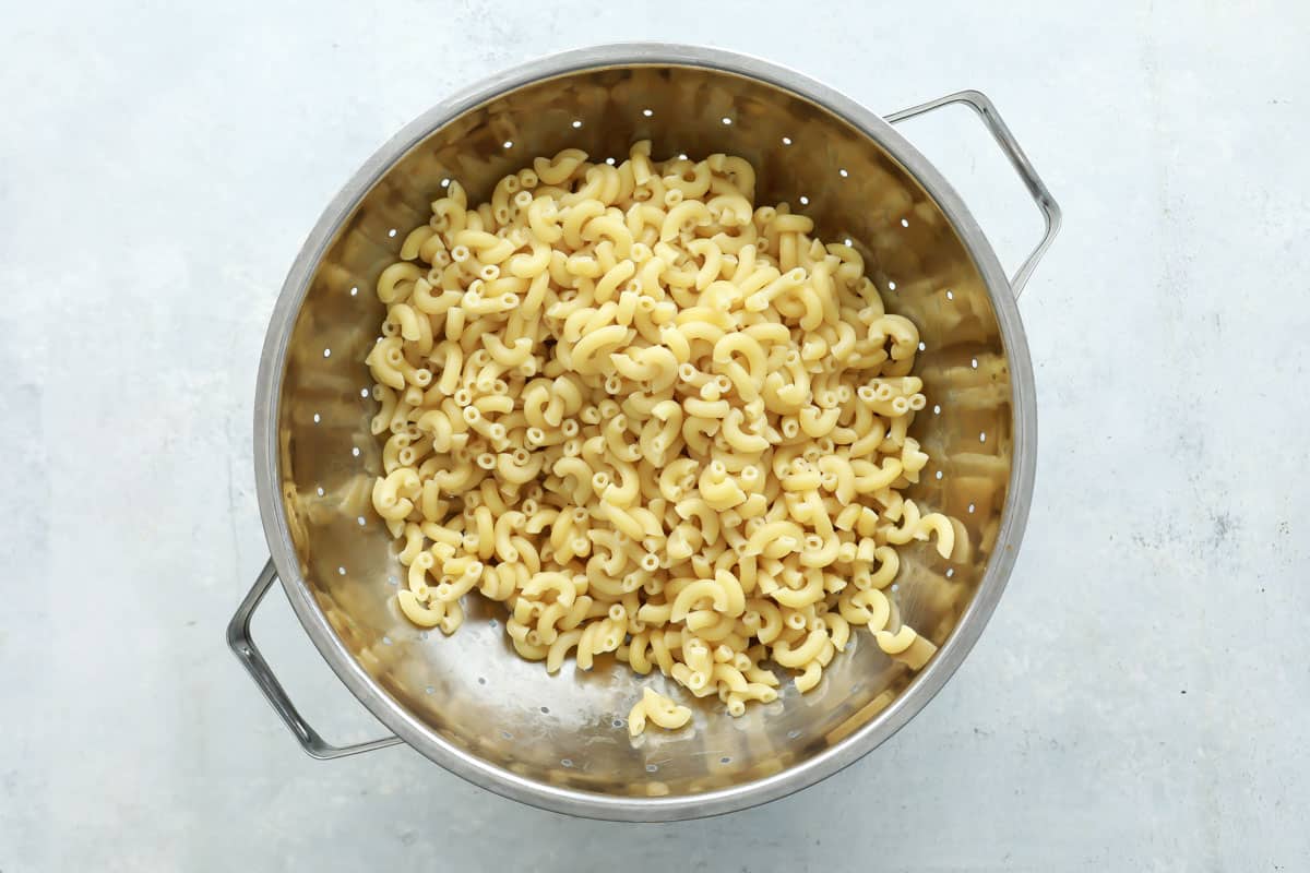 Cooked macaroni draining in a colander.