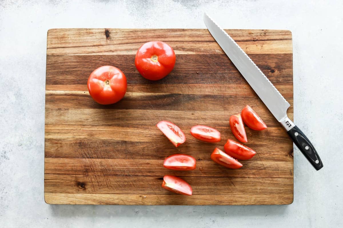 Seeding tomatoes on a cutting board.