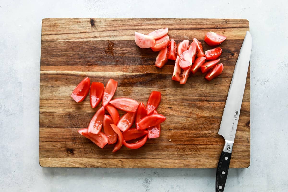 Seeding tomatoes on a cutting board.
