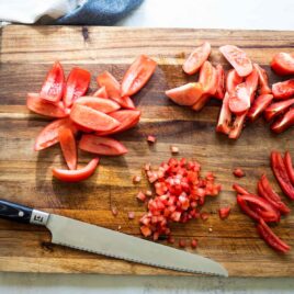 Seeding tomatoes on a cutting board.