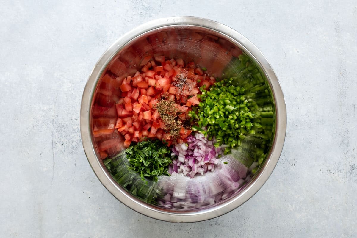Ingredients for pico de gallo in a silver mixing bowl.