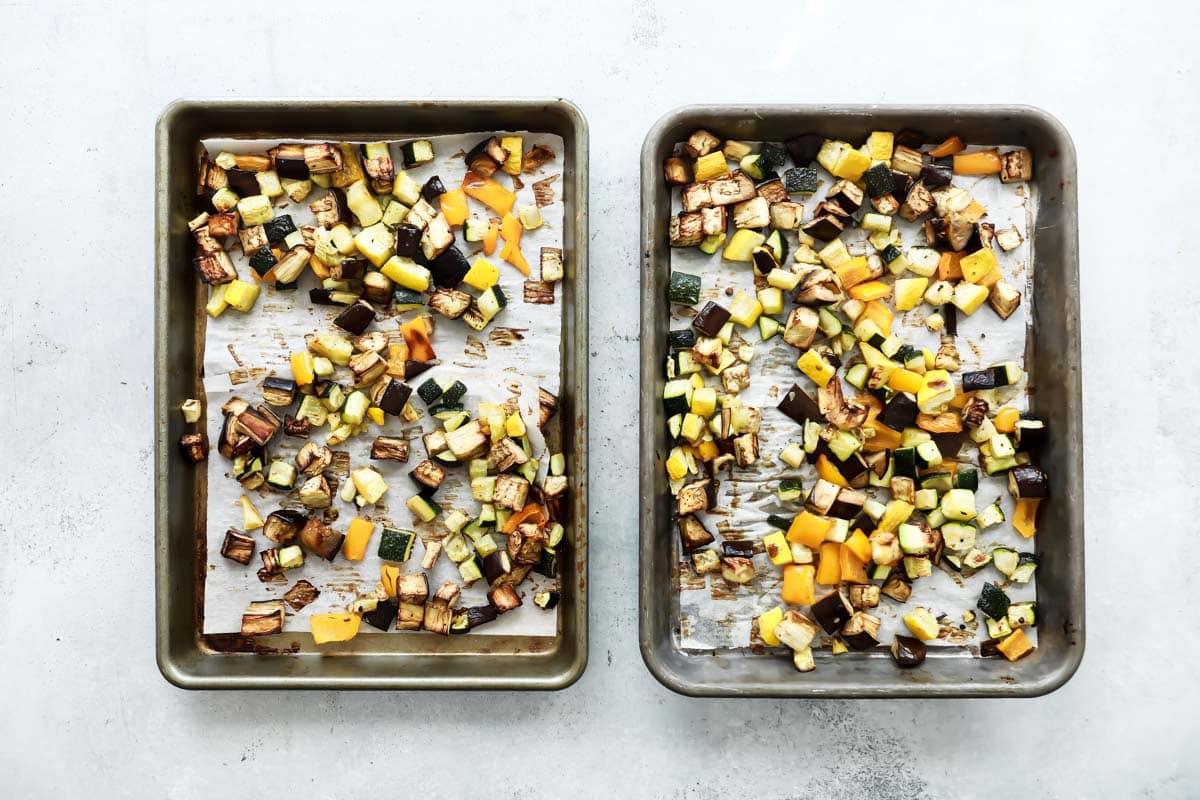 Two baking sheets full of vegetables for ratatouille.