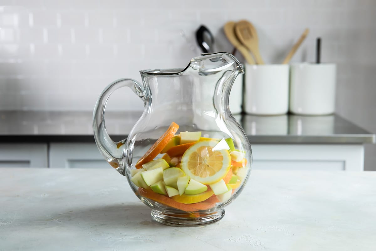 Fruit for sangria in a glass pitcher.