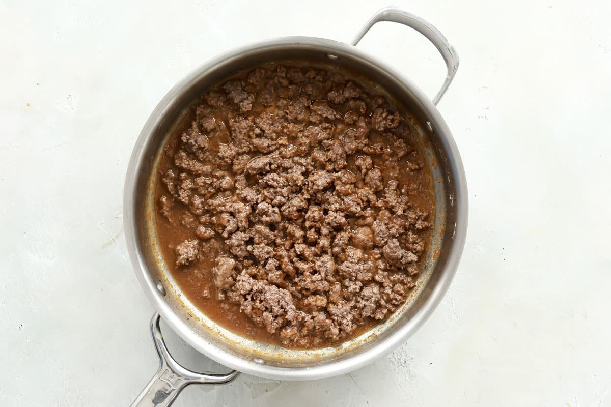 Ground beef being cooked in a silver pot.