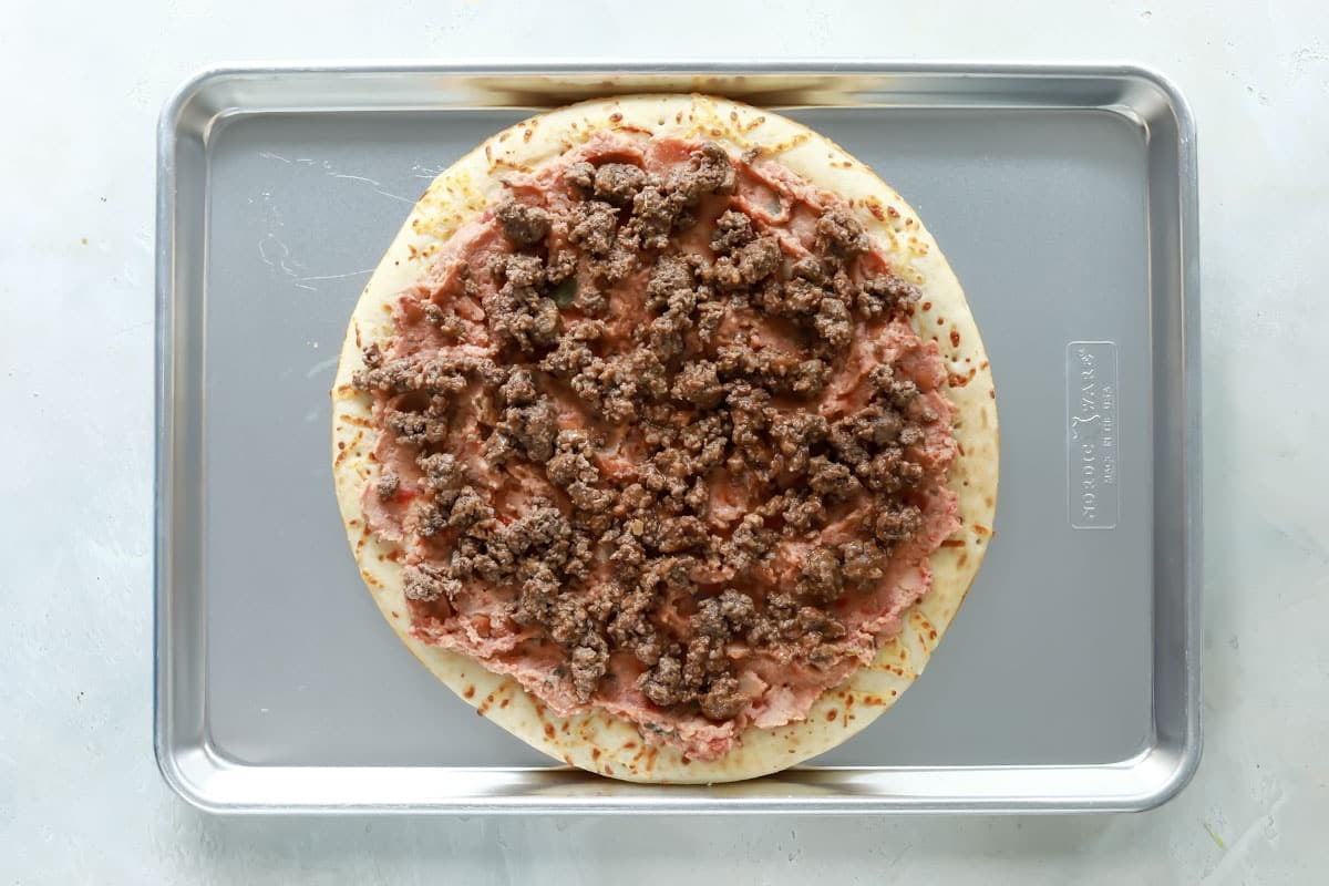 A taco pizza before being baked.