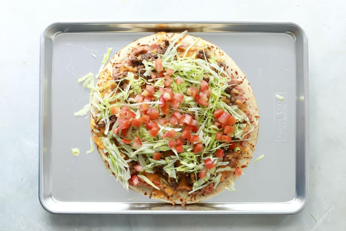 A taco pizza on a baking sheet.