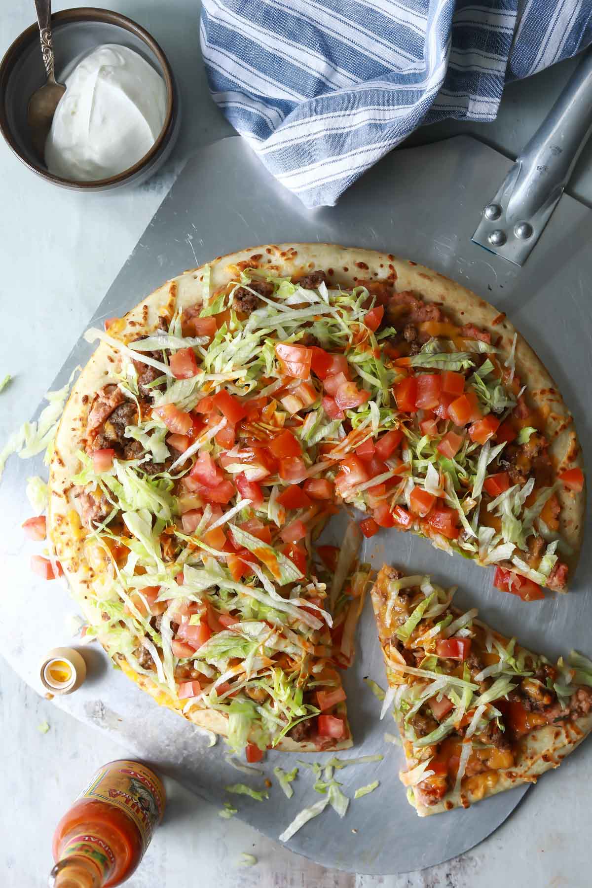 A taco pizza with a slice cut.