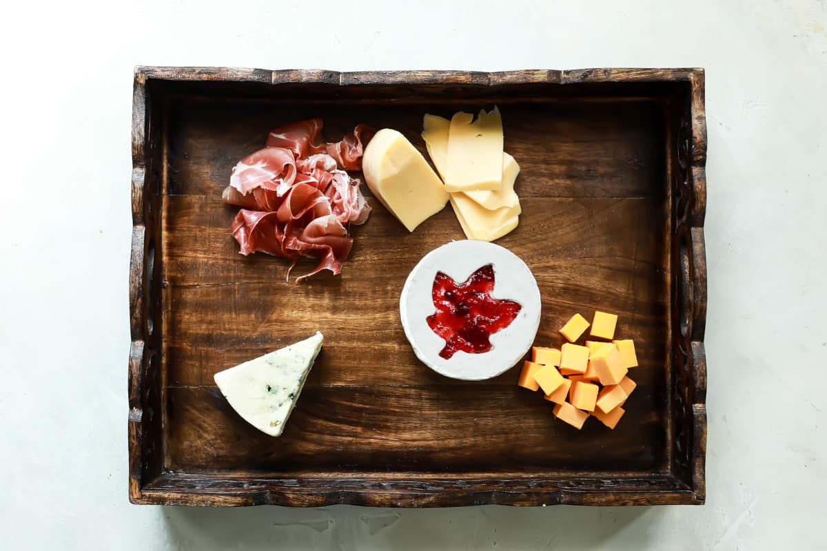 Meat and cheese on a wooden tray.