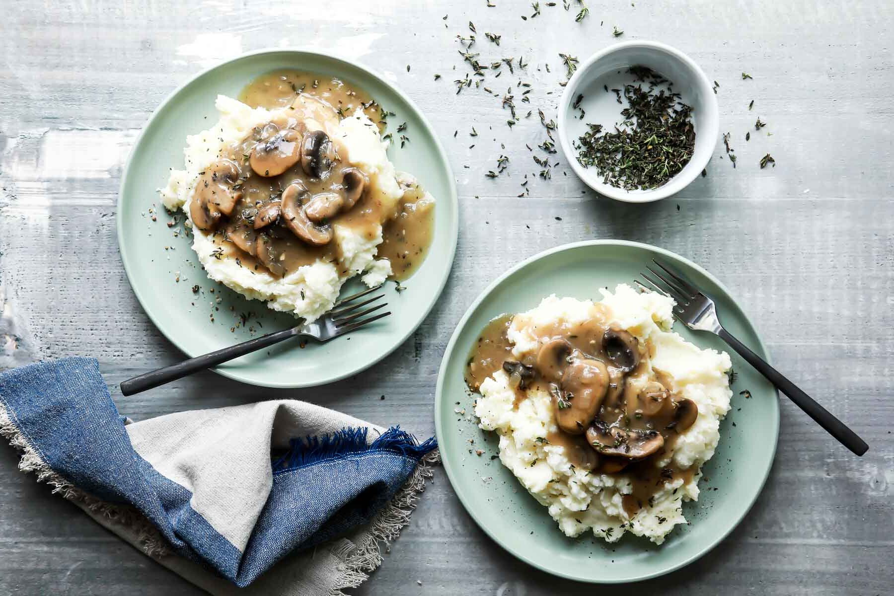 A plate of mashed potatoes with mushroom gravy on top.