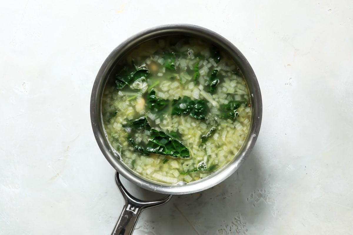 White bean and kale soup in a saucepan.