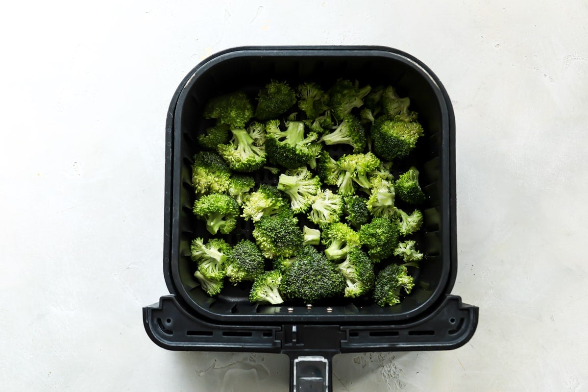 Broccoli in an air fryer basket.