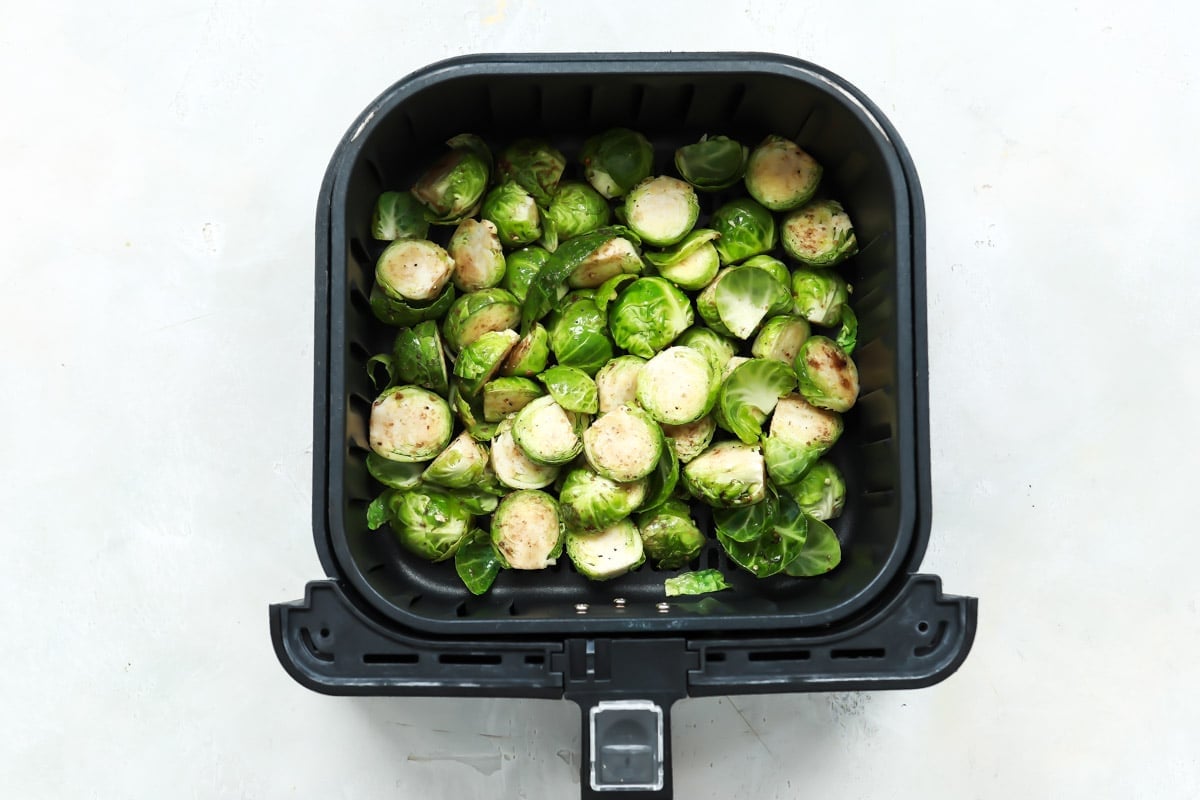 halved and quartered, seasoned brussels sprouts in basket of air fryer. 