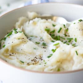 A bowl of air fryer mashed potatoes garnished with chives.