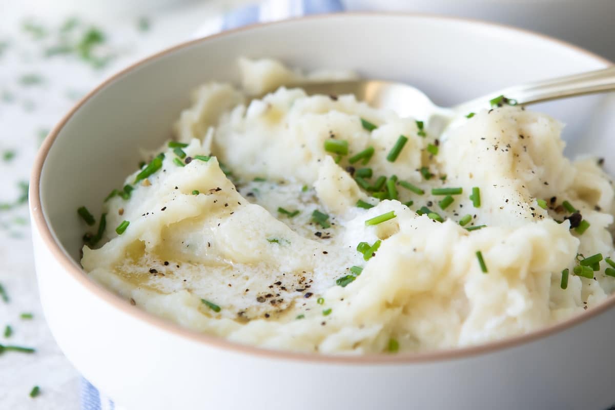 A bowl of air fryer mashed potatoes garnished with chives.
