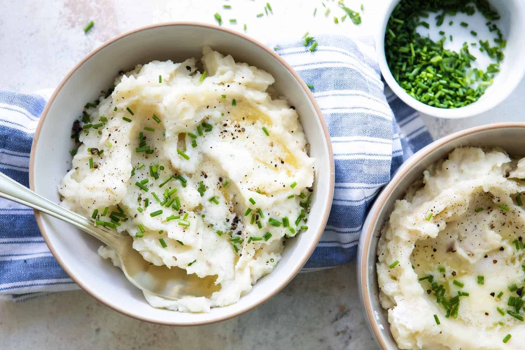 A bowl of air fryer mashed potatoes garnished with chives.