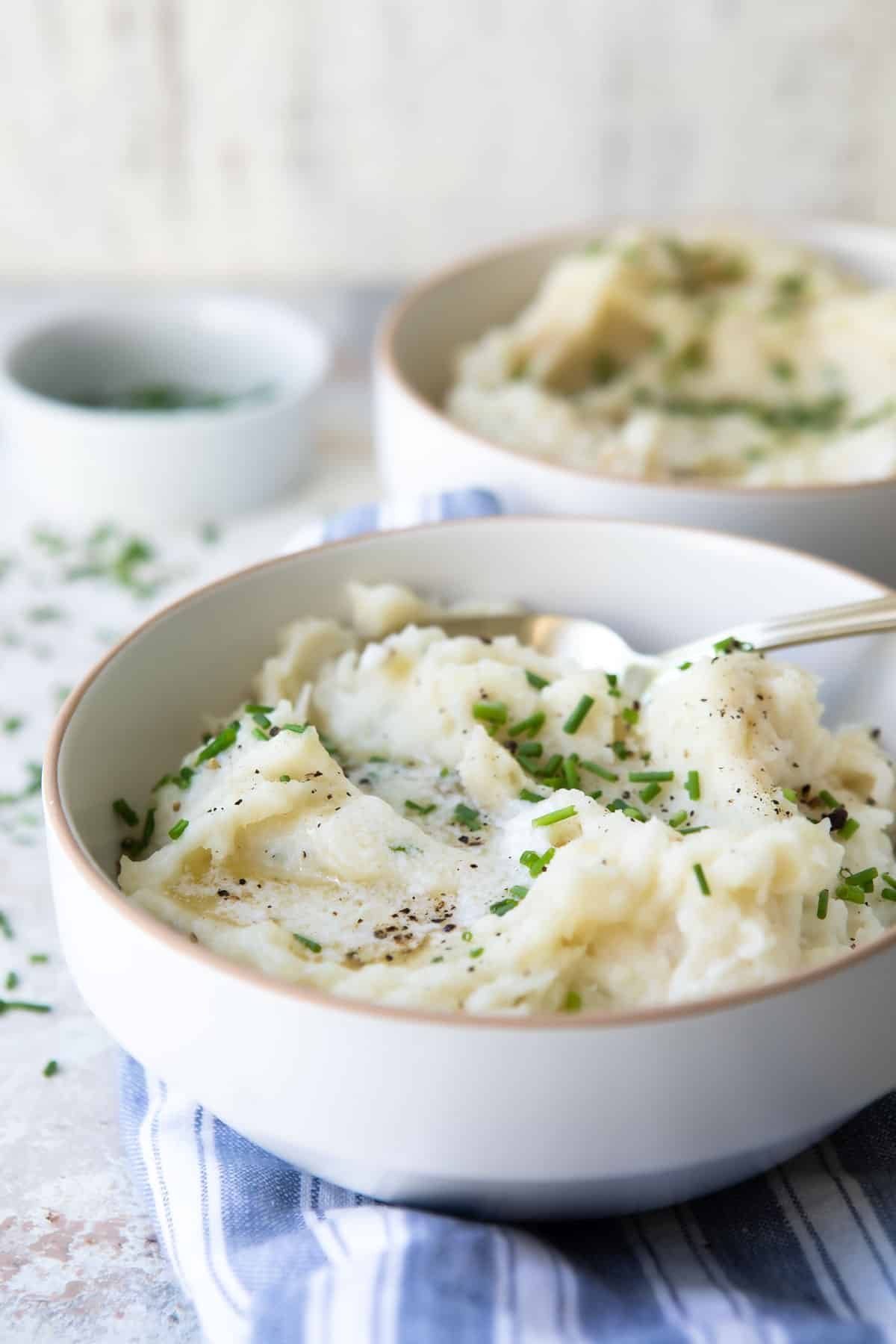 A bowl of air fryer mashed potatoes garnished with chives.